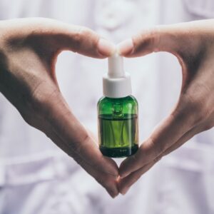 someone holding a tincture making a heart shape with their hands