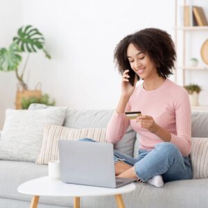 woman looking at her credit card while talking on the phone